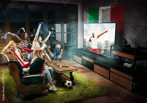 Group of friends watching TV  match  championship  sport games. Emotional men and women cheering for favourite football team of Italy with national flag. Concept of friendship  competition  emotions.