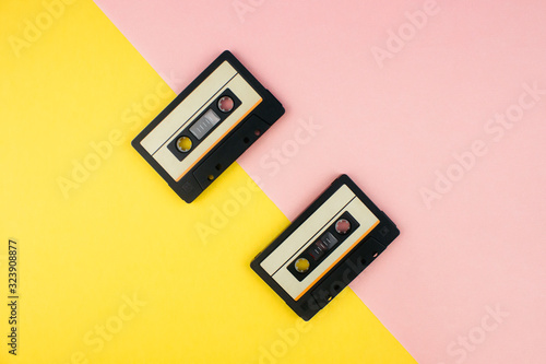 Retro audio cassettes flat lay on colorful yellow and pink background top view with copy space. Creative design in minimal 80-s style. Music, radio, dj concept. Web banner template. Stock photo.
