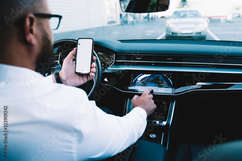 Concept of safety during wheeling in automotive vehicle, executive man checking location information while driving contemporary automobile machine using 4g wireless internet on smartphone technology