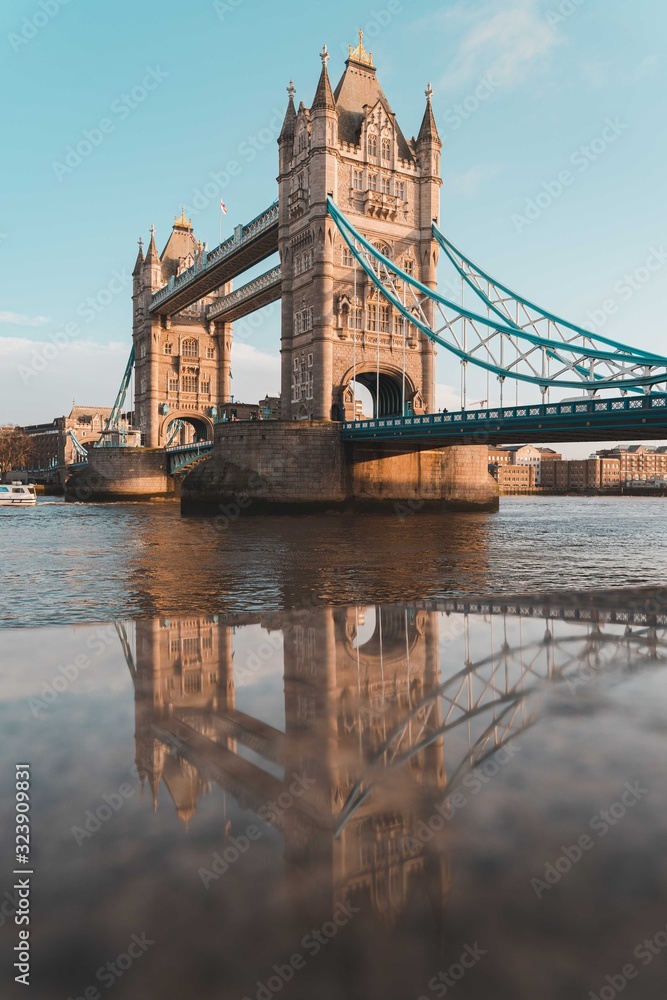 tower bridge in london reflected in the wet stone wall along the river thames