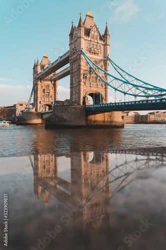 tower bridge in london reflected in the wet stone wall along the river thames