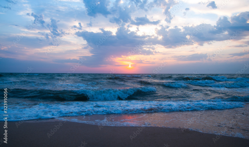 Beautiful gentle sunset on the seashore. Sunrise at sea. Waves and foam