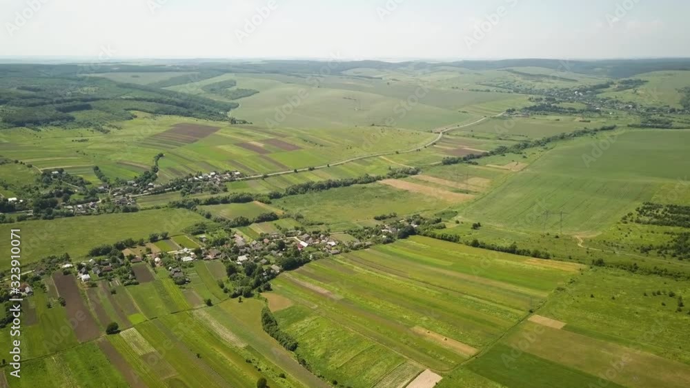 Aerial view of small village with small houses among green trees with farm fields and distant forest in summer. Aerial view of small village with small houses among green trees with farm fields and distant forest in summer.