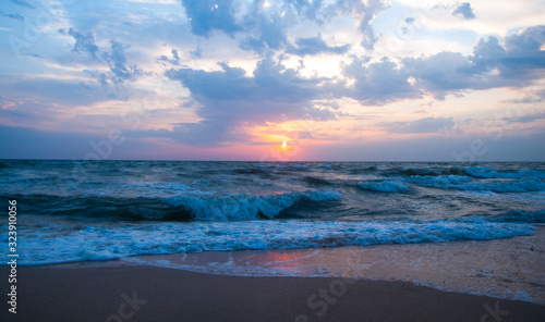 Beautiful gentle sunset on the seashore. Sunrise at sea. Waves and foam
