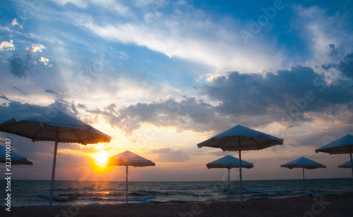 Beautiful sunset by the sea. Sunrise at sea. Umbrellas on the beach. © amdre100
