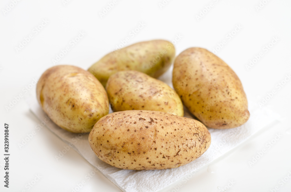 Washed raw potatoes for cooking lie on a napkin on a white table Washed raw potatoes for cooking lie on a napkin on a white table