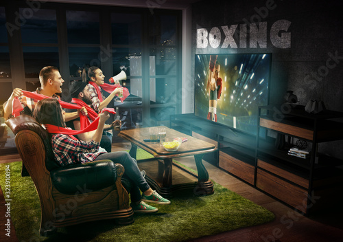 Group of friends watching TV, boxing match, championship, sport games. Emotional men and women cheering for favourite boxer, look on fighting. Concept of friendship, sport, competition, emotions.