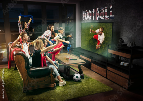 Group of friends watching TV, match, championship, sport games. Emotional men and women cheering for favourite soccer team on Great Britain with flag. Concept of friendship, sport, competition