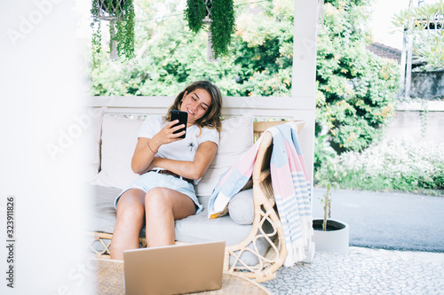 Canvastavla Young woman with smartphone relaxing on terrace