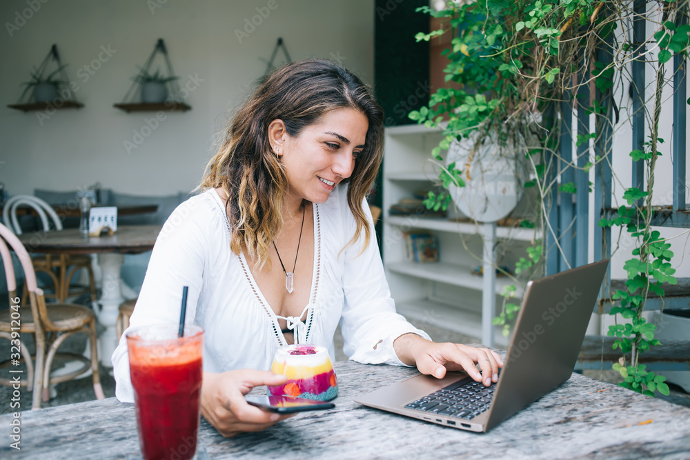 Smiling young woman typing on laptop on vacation