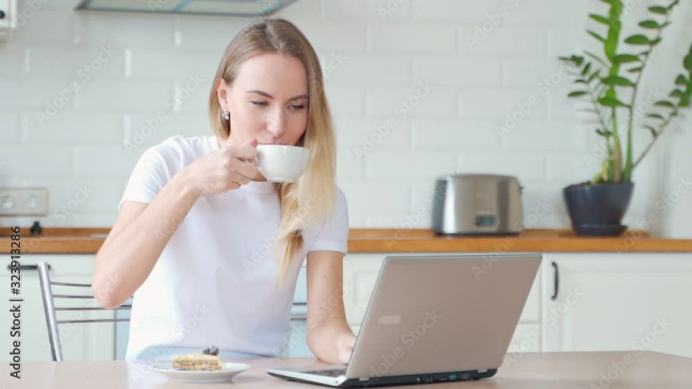 Female young woman with laptop and eating dessert cake and tea at home Female young woman with laptop and eating dessert cake and tea at home
