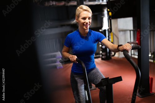 Beautiful fit woman training by riding a bicycle in a gym
