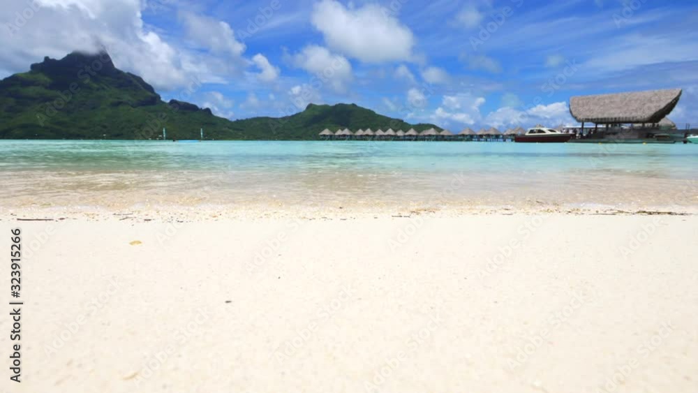 Low angle shot of splashing waves on golden beach with beautiful landscape in background,south pacific Low angle shot of splashing waves on golden beach with beautiful landscape in background,south pacific