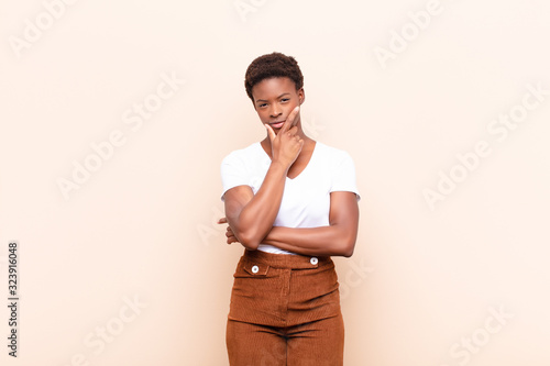 young pretty black womanlooking serious, thoughtful and distrustful, with one arm crossed and hand on chin, weighting options photo