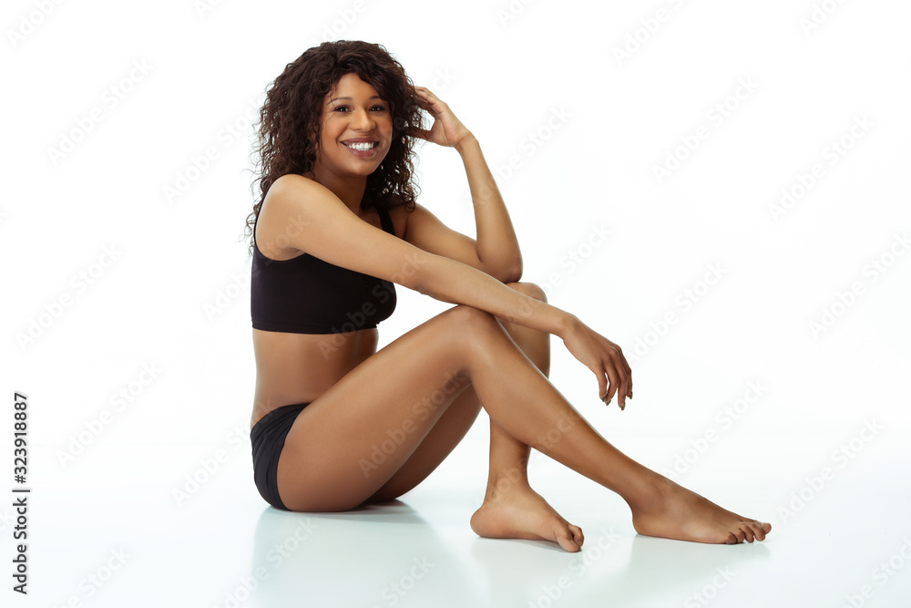 Smiling, beautiful, feminine. Slim tanned woman isolated on white studio background. African-american model with well-kept shape and skin. Beauty, self-care, weight loss, fitness, slimming concept.
