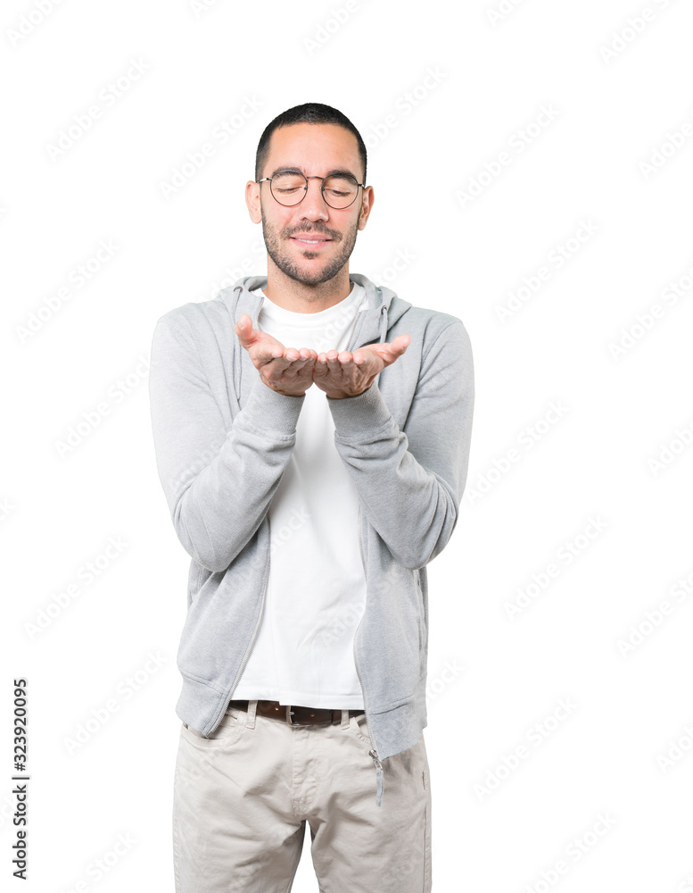 Happy young man holding something with his hand Happy young man holding something with his hand