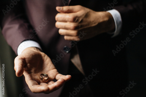 Close-up view of man's hands holding wedding rings.