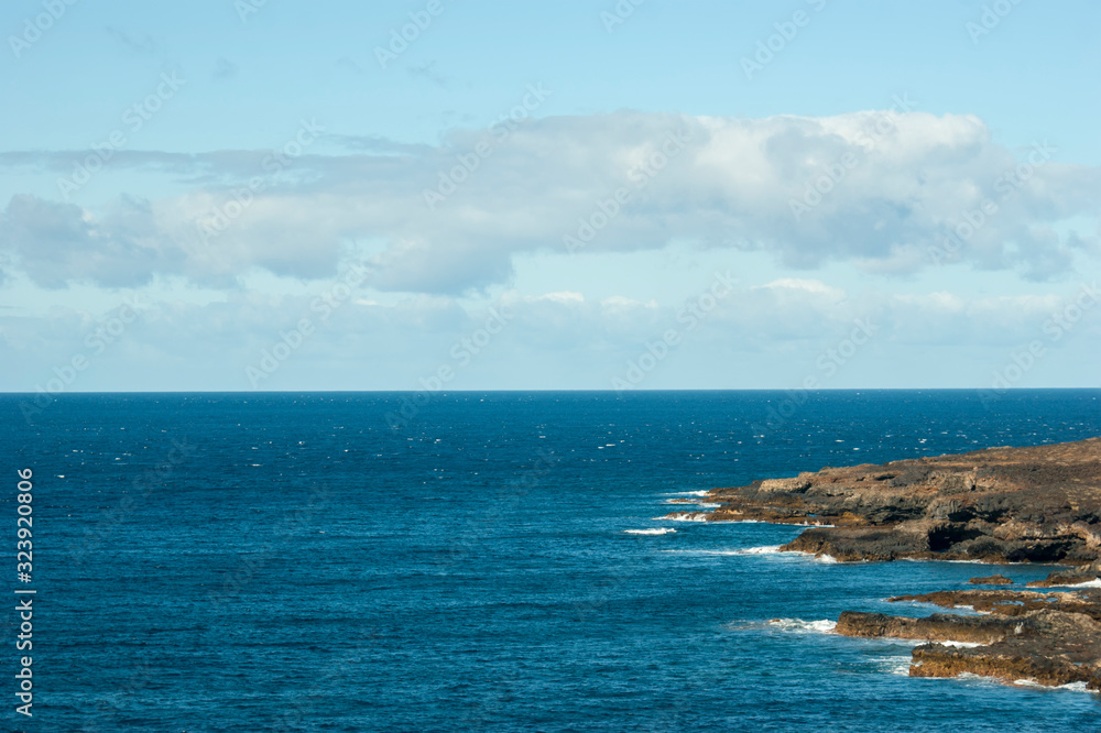 View of the rocks of the rugged rocky coast. Meeting of the sky, sea and earth. Waves beating against the rocks at the rugged coast.