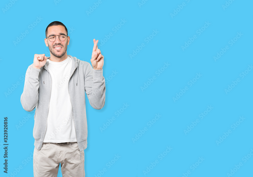 Concerned young man doing a crossed fingers gesture Concerned young man doing a crossed fingers gesture