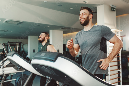 Two young man running on treadmill at gym photo