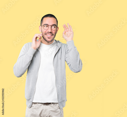 Happy young man smiling and making a gesture of trying to hear something © agongallud
