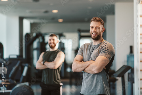 Two Handsome young man posing in a gym and looking at the camera with smile