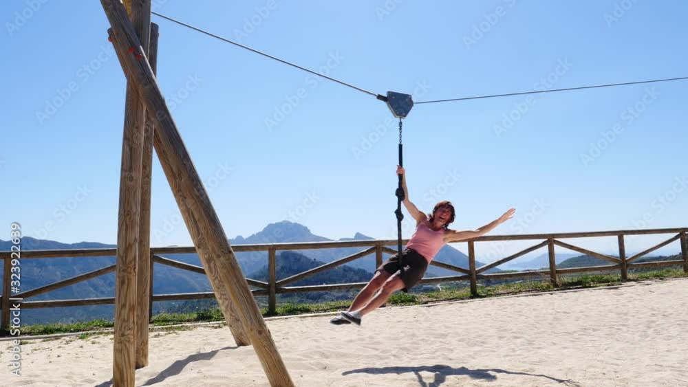 Adult freedom woman tourist having fun on zipline, descend on rope, cable aerial ropeslide. Mountains rest area place in Spain Alicante region. Costa Blanca holiday Adult freedom woman tourist having fun on zipline, descend on rope, cable aerial ropeslide. Mountains rest area place in Spain Alicante region. Costa Blanca holiday