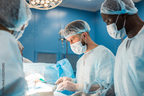 An international team of doctors performs a complex surgical operation on a patient under anesthesia. Modern operating room and experienced surgeons save lives