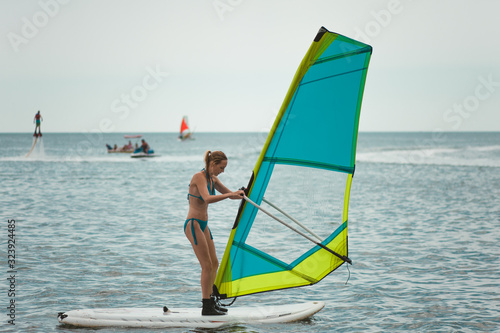 Young slim woman with sports figure learns to windsurf