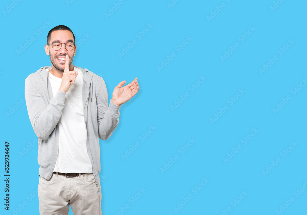 Amazed young man asking for silence gesturing with his finger Amazed young man asking for silence gesturing with his finger