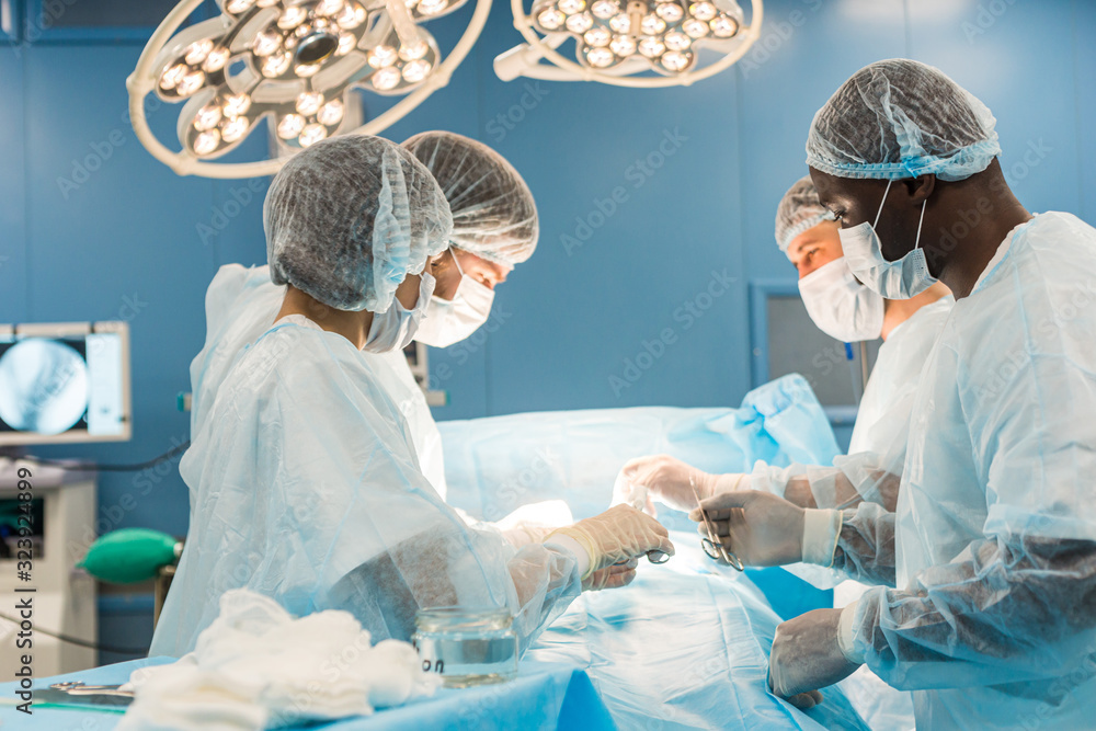 An international team of doctors performs a complex surgical operation on a patient under anesthesia. Modern operating room and experienced surgeons save lives An international team of doctors performs a complex surgical operation on a patient under anesthesia. Modern operating room and experienced surgeons save lives