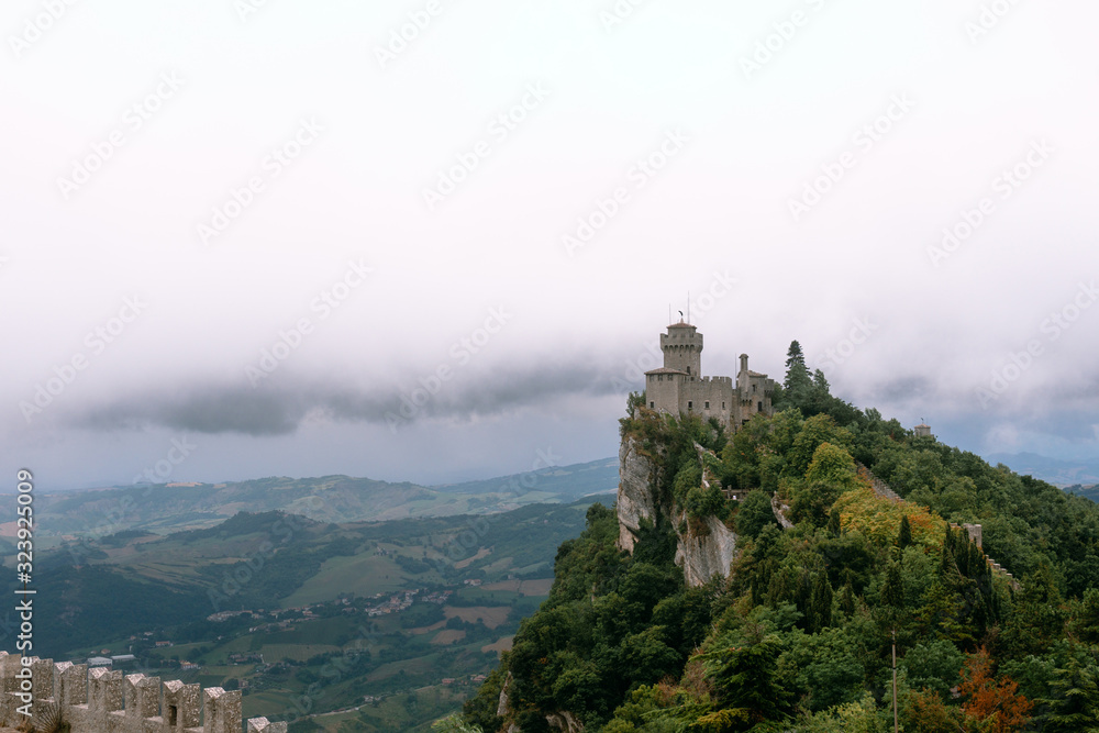 View from the top of the mountain to the medieval fortification. Dramatic mystical weather with fog. Castle in San Marino (Seconda Torre) Second Tower, Copy space