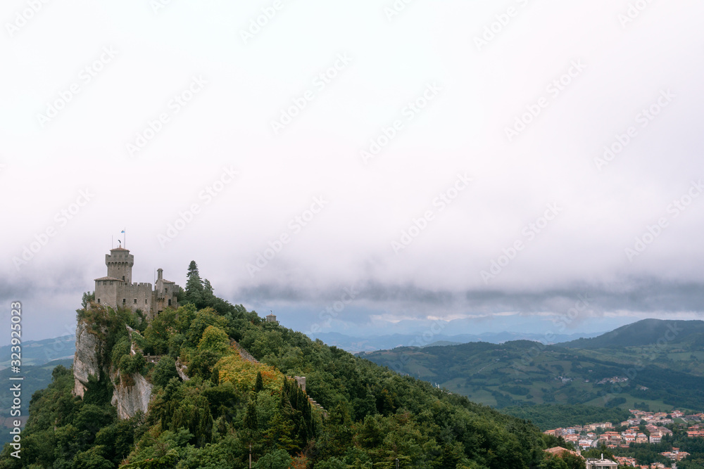 View from the top of the mountain to the medieval fortification. Dramatic mystical weather with fog. Castle in San Marino (Seconda Torre) Second Tower, Copy space