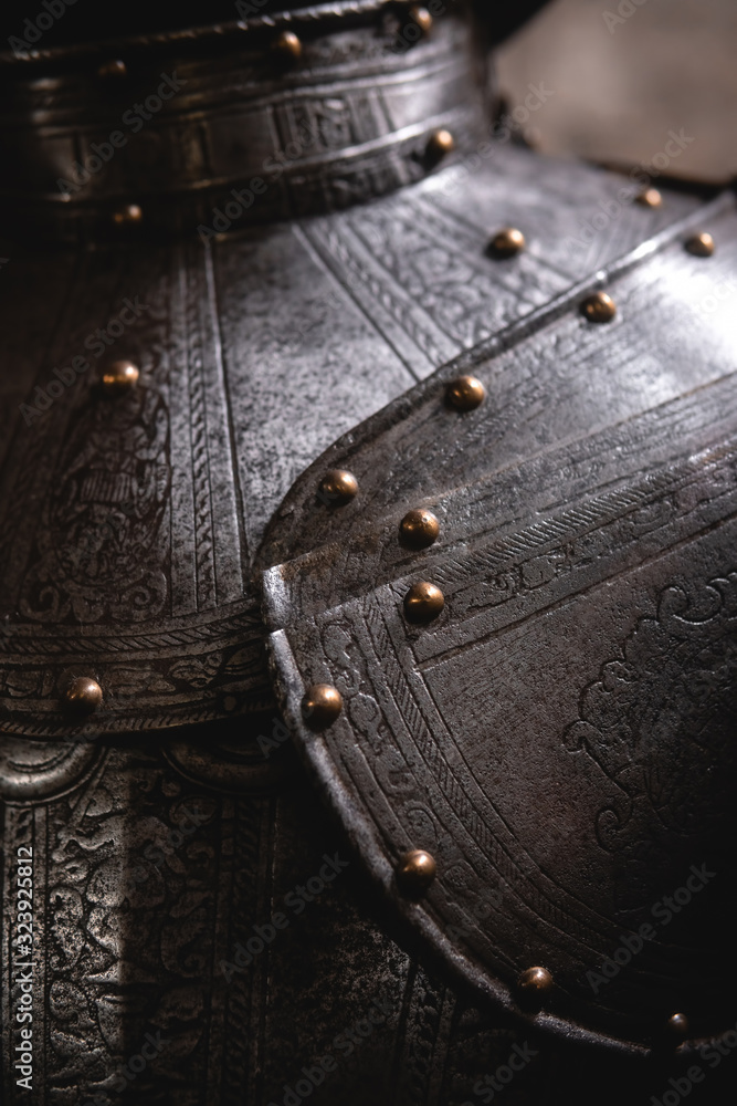 Close up detail Background with armour of the medieval knight. Metal protection of the soldier. Steel Plate. Rivets and engraving, dark light