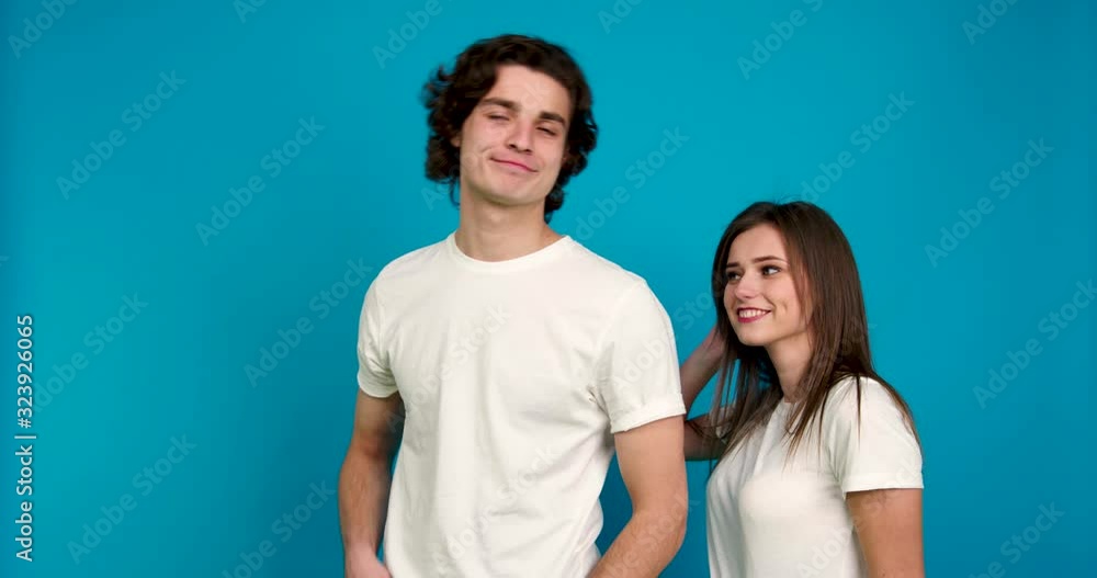 Smiling couple posing together, embracing and showing thumb up isolated on blue background Smiling couple posing together, embracing and showing thumb up isolated on blue background