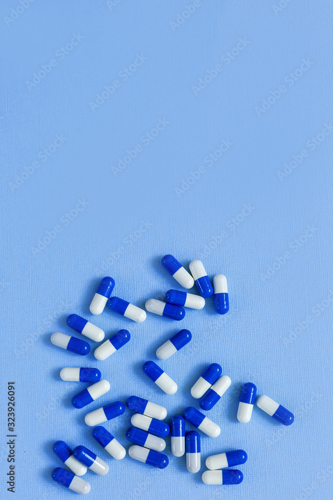 Medicinal capsules of white and blue color on the background.
