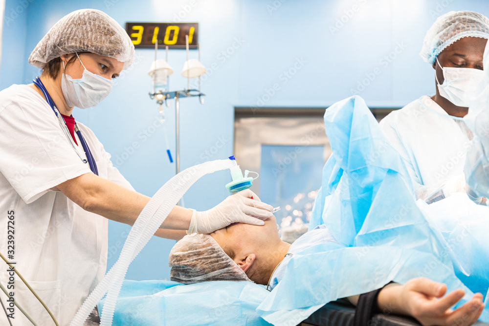 Portrait of an anesthesiologist among a team of doctors monitors instrument readings and patient status Portrait of an anesthesiologist among a team of doctors monitors instrument readings and patient status