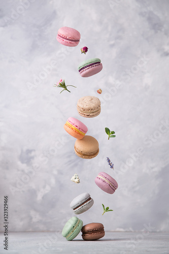 Sweet macaroons cookies falling in motion on grey background. Pastel colored flying macaroons with ingridients. Food, culinary and cooking concept levitation