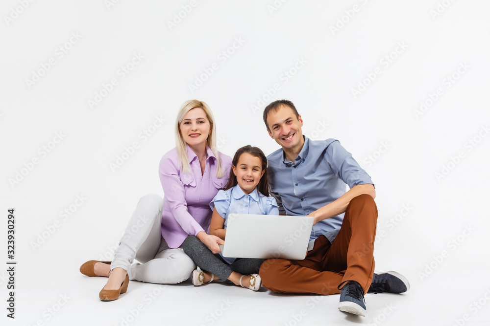 Happy family lying down on the floor while surfing on internet online with laptop, isolated over white
