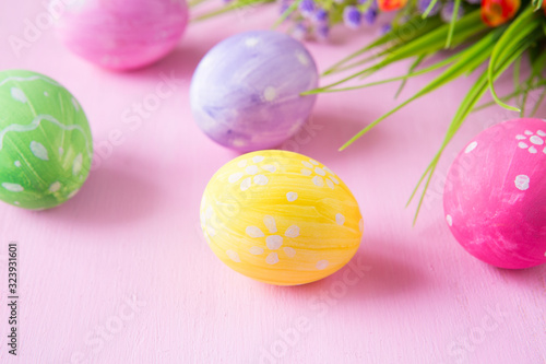 Easter eggs with wild flowers on a wooden pink table background