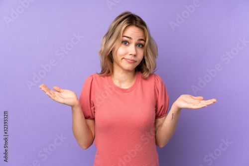 Teenager Russian girl isolated on purple background making doubts gesture © luismolinero