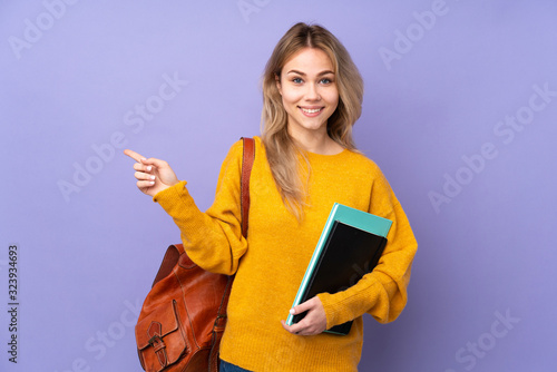 Teenager Russian student girl isolated on purple background pointing finger to the side
