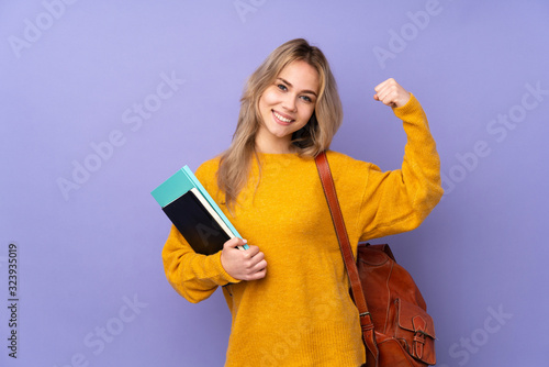Teenager Russian student girl isolated on purple background doing strong gesture