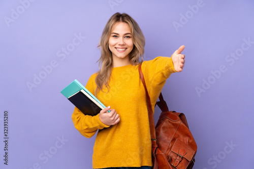 Teenager Russian student girl isolated on purple background presenting and inviting to come with hand