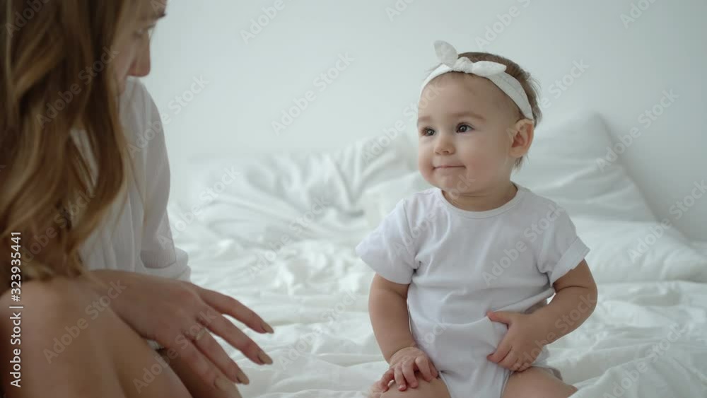 Adorable Infant Baby Girl Looking At Her Pretty Mom On Bed Adorable Infant Baby Girl Looking At Her Pretty Mom On Bed