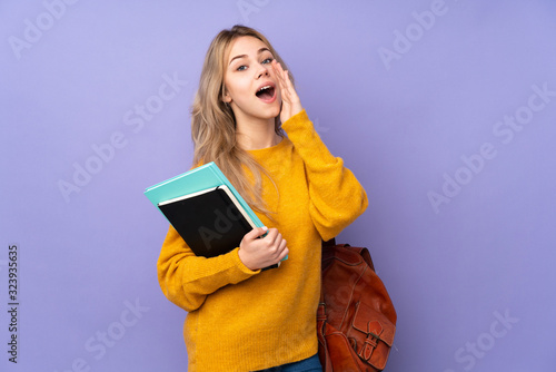 Teenager Russian student girl isolated on purple background shouting and announcing something