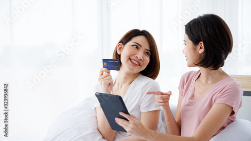 Two Asian women use tablet for online shopping purpose and pay with credit card.