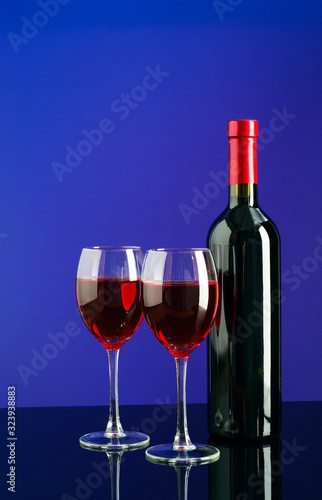 Glasses and bottle of wine on bright blue background