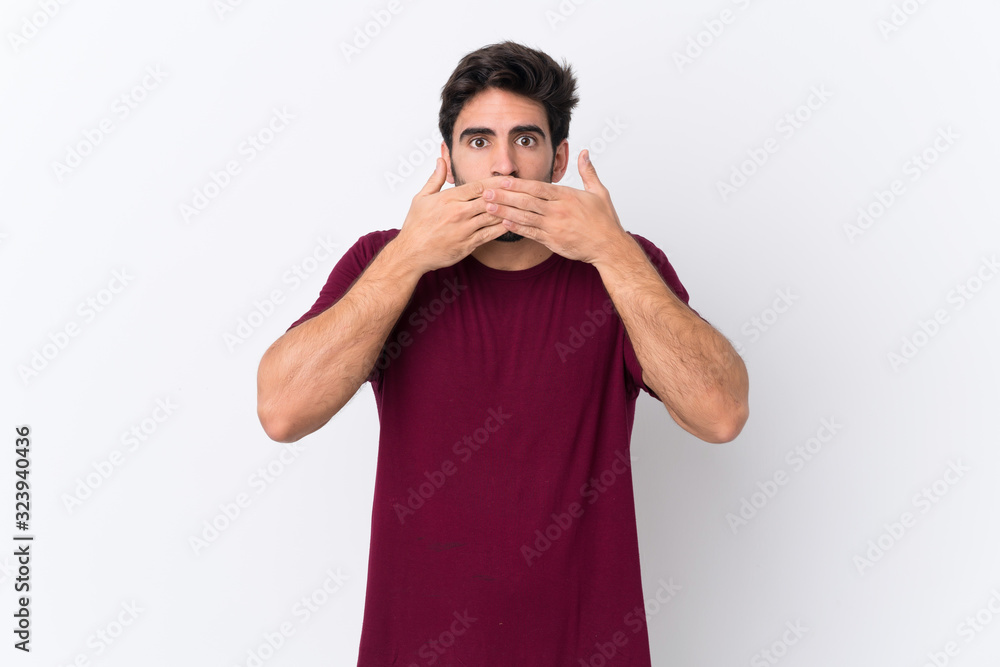 Young handsome man with beard over isolated white background covering mouth with hands Young handsome man with beard over isolated white background covering mouth with hands