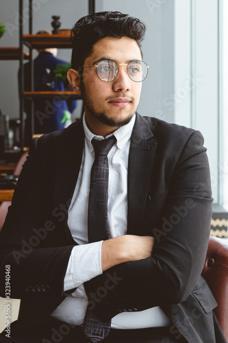 Portrait of a young successful businessman in a suit in the office. Close-up sitting in a chair by the window